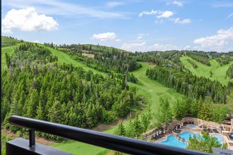 A captivating overhead view of the St Regis Mountainside View Queen reveals a vibrant green mountain landscape, featuring a golf course, lush trees, and a pool area under a bright blue sky.