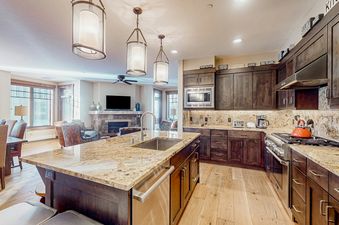 A kitchen with dark wood cabinets, granite countertops, and stainless steel appliances.