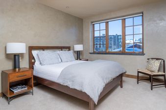 A bedroom with a large window that overlooks a snowy mountain scene.