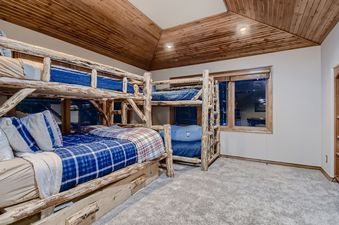 The image captures a cozy bedroom featuring rustic wooden bunk beds with blue and plaid bedding.