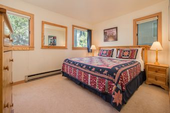 Inviting bedroom at Rendezvous A2 featuring a large bed with a rustic patchwork quilt, wood furnishings, and natural light.