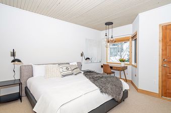 A bedroom with a king-size bed, a fuzzy throw, and a desk by the window