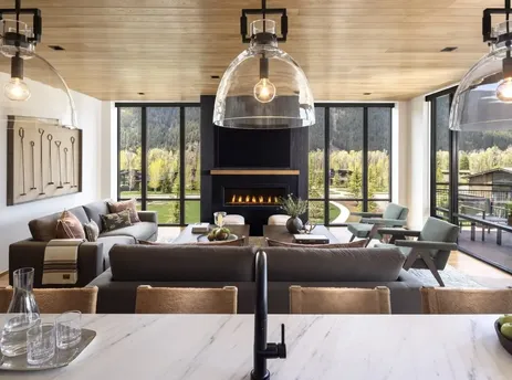 A luxurious living room in The Sylvan Lodge Two Bedroom Canopy Suite with panoramic mountain views, a modern fireplace, and comfortable seating.