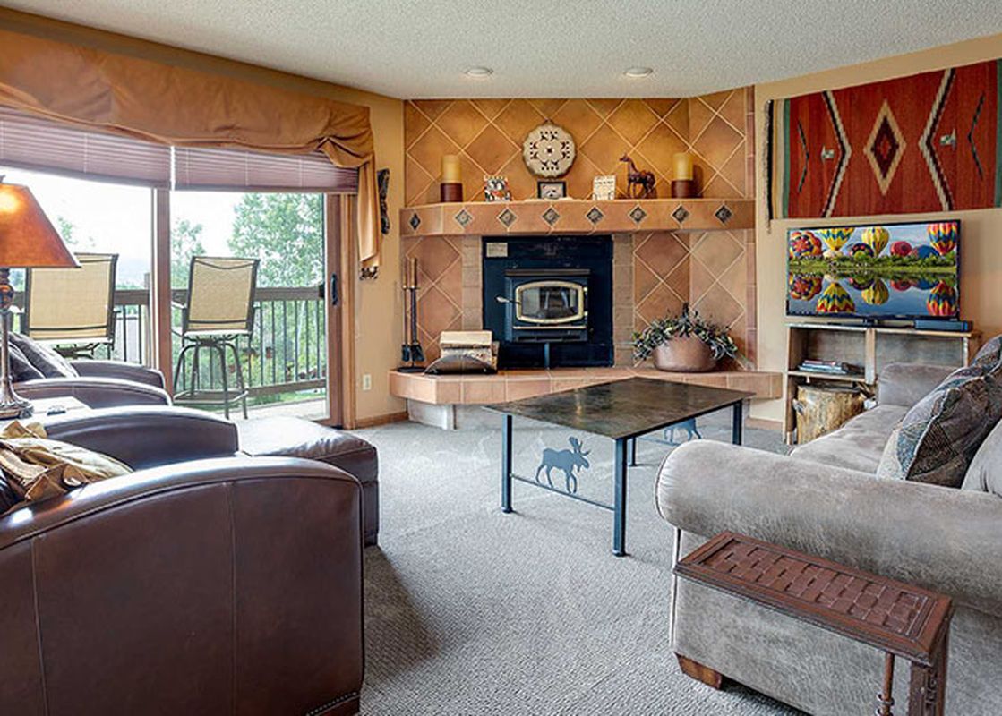 A cozy living room with a fireplace, comfortable sofas, and a large window offering an outdoor view at Ranch at Steamboat RA501.