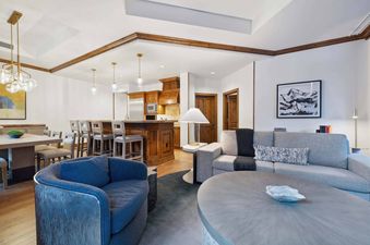The Aspen 03B living room features a grey sofa, a wood coffee table, and a large blue armchair.