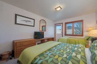 Cozy bedroom at Teewinot D4 with two beds, green bedding, wooden furniture, and a window showing the exterior view.