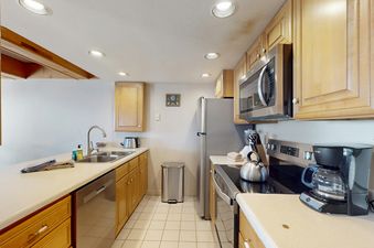 A modern kitchen at Vail International 003 with light wood cabinets, stainless steel appliances, and a double sink.