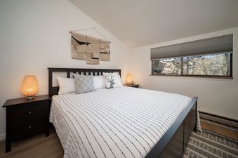 The bedroom in Beaver Village 332 features a large bed with a black frame and a white and black striped comforter, flanked by two black nightstands.