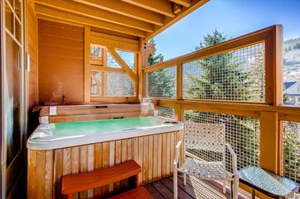 A private outdoor hot tub at Town Pointe B203, set on a wooden deck with mountain views.