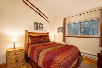 The bedroom in Beaver Village 1734 features a queen-sized bed with a colorful striped comforter, two nightstands with lamps, and a window.