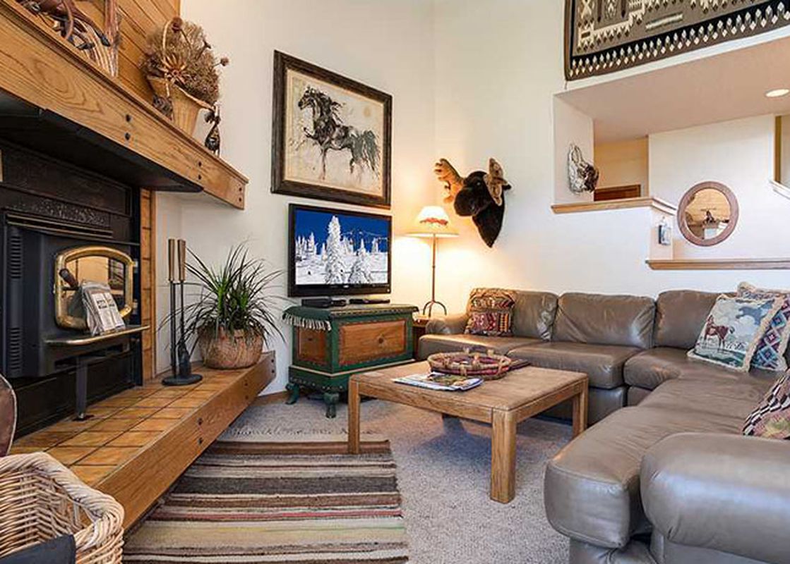 The Ranch at Steamboat RA510's living room features a fireplace, a large leather sectional sofa, a wooden coffee table, a TV, and rustic decor.