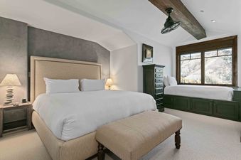 A luxurious master bedroom at Silver Strike Lodge 705 features a king-size bed, elegant decor, and a window seat offering stunning mountain views.
