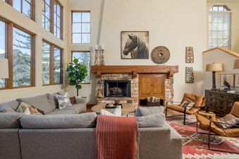 A spacious living room with a fireplace, large windows, and a comfortable sectional sofa.