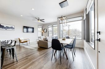 A modern open-concept living space with a dining area, living room, and large windows showing a snowy landscape.