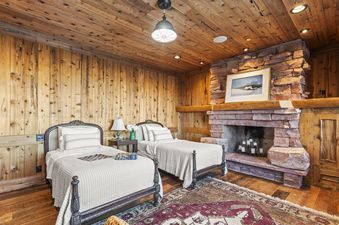 The Treehouse in Canyons Village features a cozy bedroom with two twin beds, a stone fireplace, and a warm, wood-paneled interior.