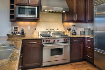 The kitchen in Lumiere Four Bedroom Residence has stainless steel appliances, dark wood cabinets, and a large, granite countertop.