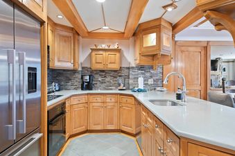 A modern kitchen in Lodge Tower 387 3BR with light wood cabinets, light countertops, and a tiled backsplash, featuring stainless steel appliances.