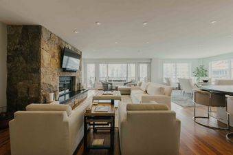 The living area of Sanctuary Chalet at One Beaver Creek is spacious and bright, featuring comfortable seating and a stunning stone fireplace.