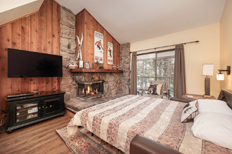 A cozy bedroom with a fireplace and a large bed covered with a striped comforter.