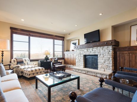 A spacious and inviting living room at Silver Star 1205 with a stone fireplace, comfortable seating, and large windows offering scenic mountain views.