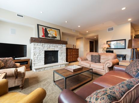 The comfortable and elegantly furnished living area at Silver Star 4202, showcasing a stone fireplace, plush seating, and a flat-screen television.