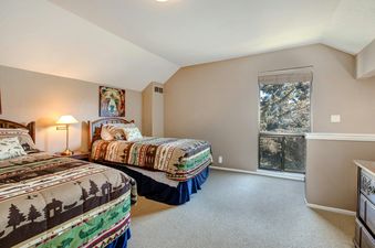 A bedroom with two twin beds with a wooded view from a window.