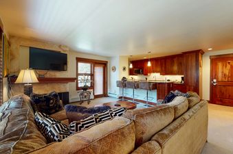 A living room with a large sectional sofa, a fireplace, and a flat screen TV.