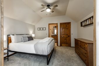A primary bedroom at Southfork Retreat with a bed, dresser, and a doorway leading to an ensuite bathroom.