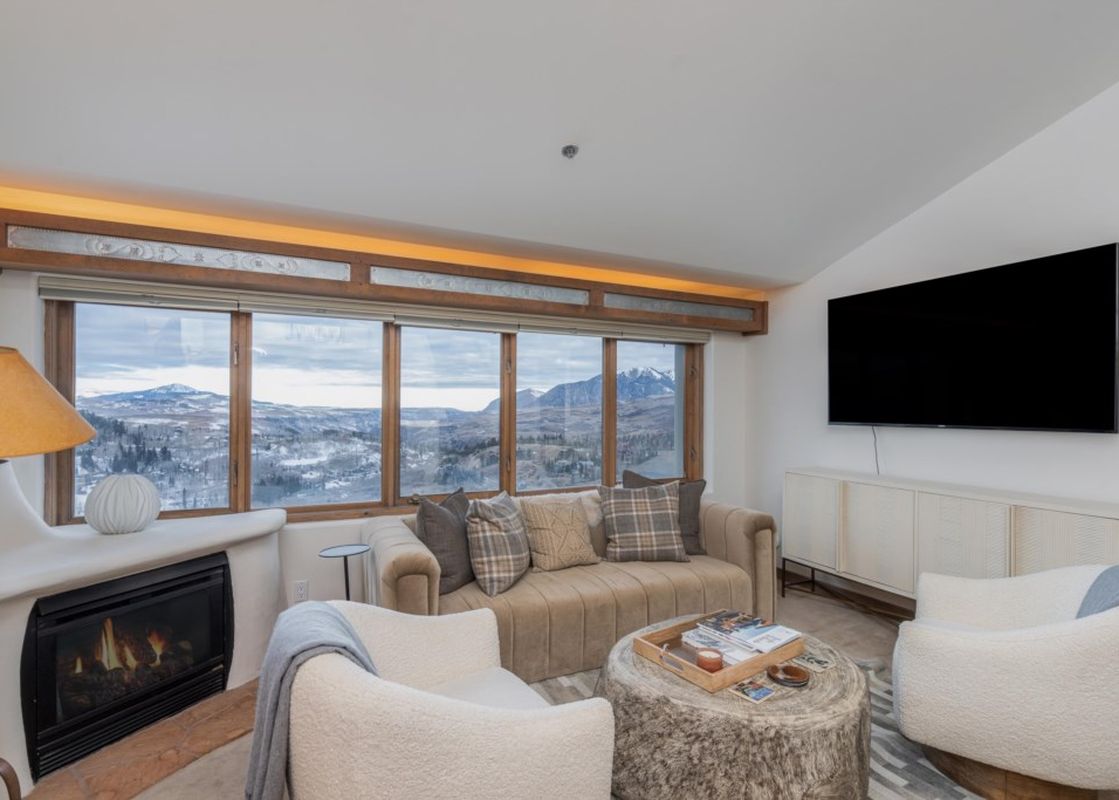 Living room interior with fireplace and mountain view.