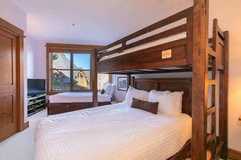 A bedroom with a bunk bed and a window with a view of the surrounding area.