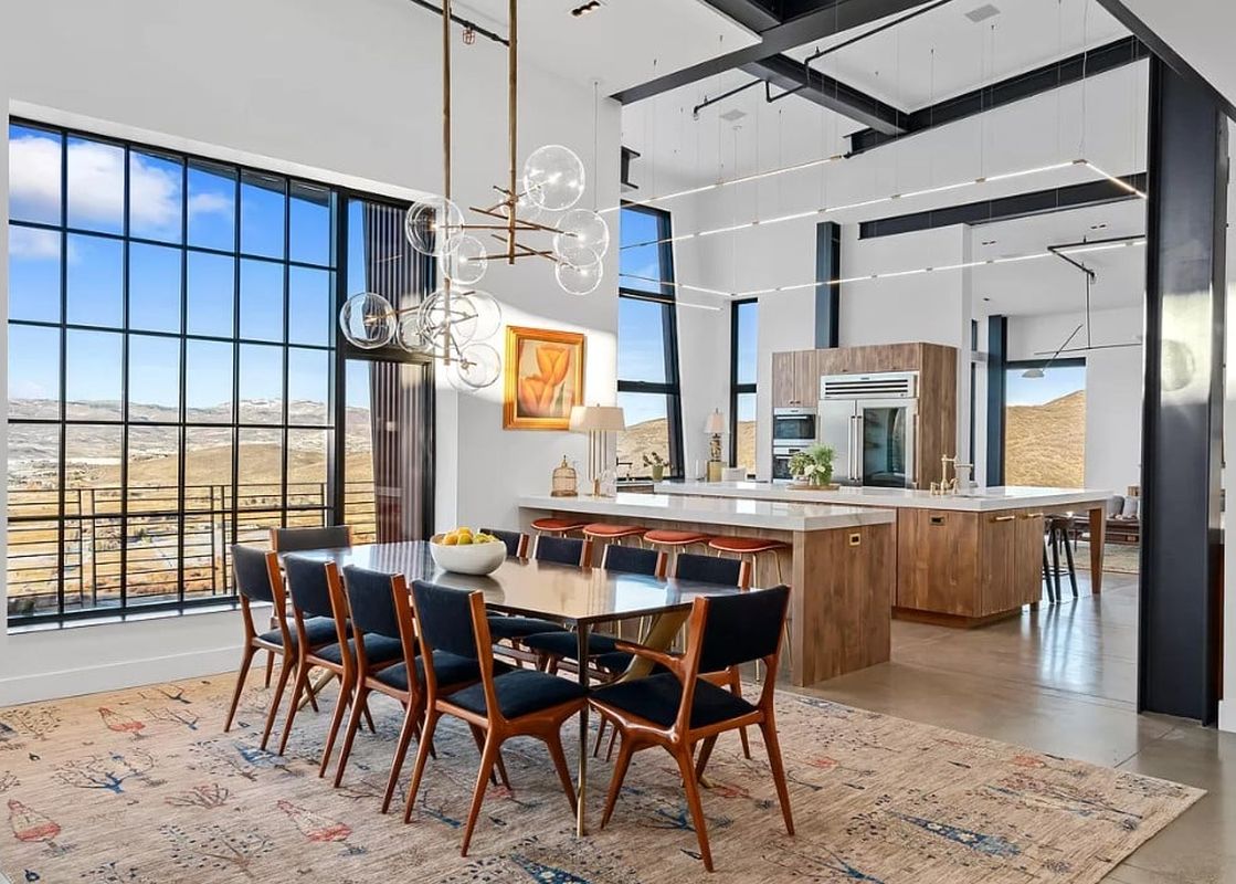 A spacious, modern dining room and kitchen with a large window offering expansive views of an outdoor landscape.