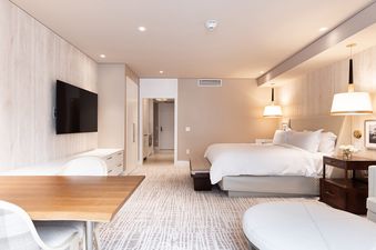 A hotel room with a king size bed, a large TV, and a table and chairs.