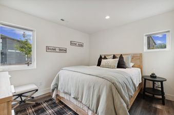 A cozy bedroom with a queen-size bed, a light wood frame, and blue bedding, featuring rustic wall decor and a small side table with a lamp.