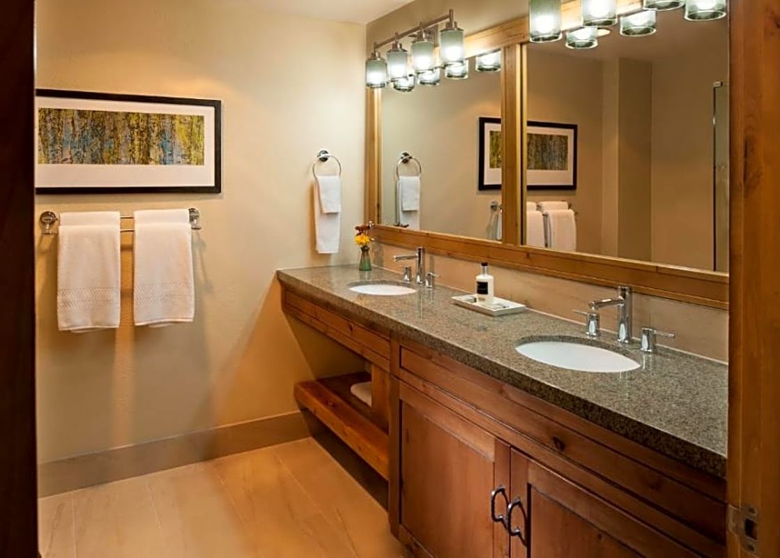 The bathroom features a spacious vanity with two sinks, granite countertops, and wooden cabinetry.