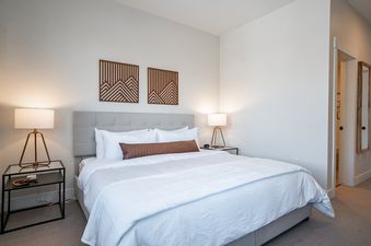 A modern and cozy bedroom with a large king bed and stylish bedside lamps at Hideaway Haven.