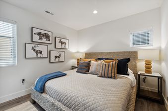 A cozy bedroom with a woven bed, rustic animal art, and warm lighting in Quarry A35.