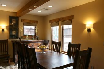 A large dining table with chairs, a side board, and windows in The Chateaux Deluxe Studio.