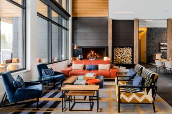 A living room area with a fireplace, large windows, and comfortable furniture in Moonlight Basin 212 Lakelodge.