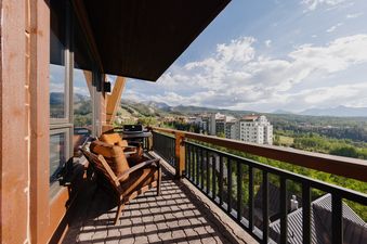 A private balcony at Skyline Views at See Forever features outdoor seating, a barbecue grill, and breathtaking mountain and valley views.