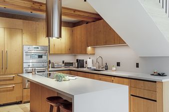 A modern kitchen in Tyrolean 6 with warm wood cabinets, a large island, and stainless steel appliances.