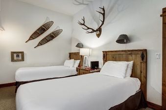 A cozy bedroom with two single beds, antler decor, and snowshoes on the wall.