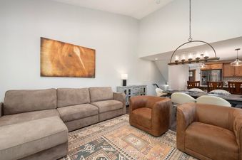 A cozy and inviting living area in Vasquez Creek Townhomes 8 featuring a large sectional sofa, two leather armchairs, and a decorative rug.