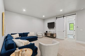 A cozy living room at Dakota Haven with a large blue sectional sofa, a wall-mounted TV, and a sliding barn door leading to another room.