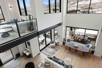 An expansive, modern living room at SkyRidge 1718 with large windows showcasing a snowy mountain view.