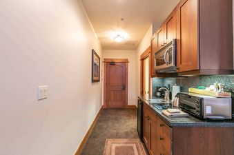 A small galley kitchen with wood cabinets, stainless steel appliances, and a granite countertop.