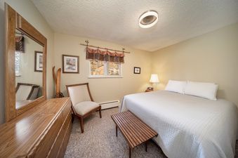 A cozy bedroom with a large bed, wooden furniture, and a window.