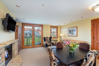 The living area of Lost Creek Two Bedroom Condo has a large fireplace, a dining table with four chairs, and a couch.