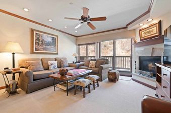 The living area features a comfortable L-shaped sofa, a coffee table with decorative items, and a fireplace with a mantelpiece, creating a cozy and inviting atmosphere.