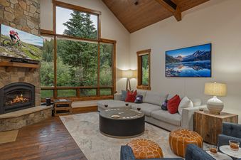 The living area of the Royal Retreat features a warm fireplace, a comfortable sectional sofa, a large smart TV, and expansive windows that offer stunning views of the surrounding nature.