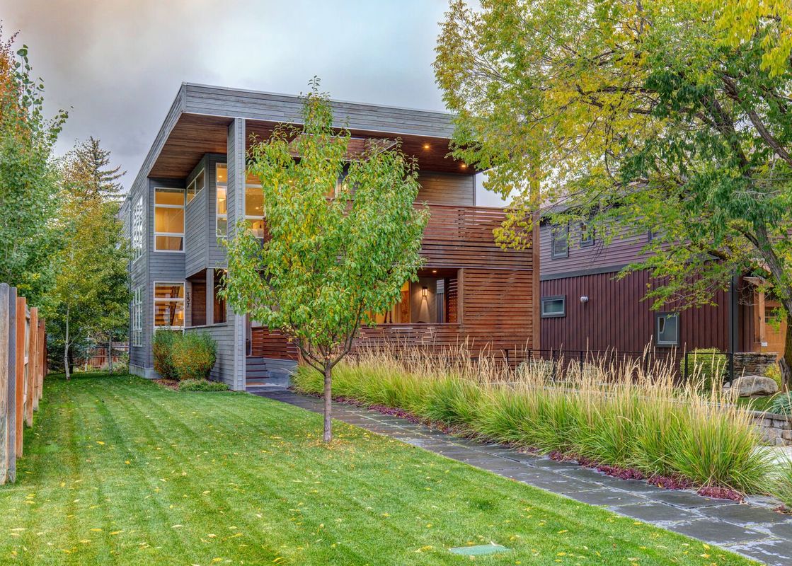 A modern home with a wooden deck and a grassy lawn.
